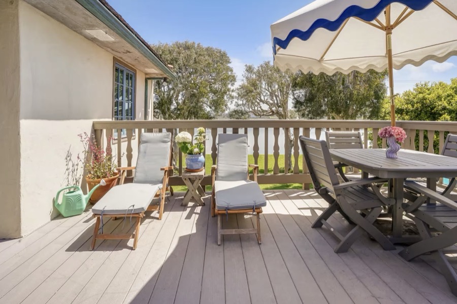 The sun deck with loungers and a dining table above the lagoon lawn