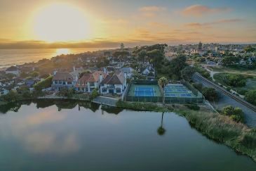 Aerial of the lagoon, courts, and community rooftops at sunset