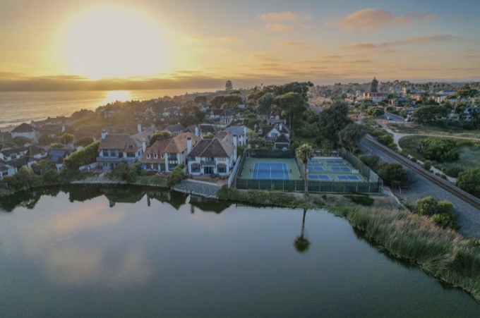 Aerial of the lagoon, courts, and community rooftops at sunset