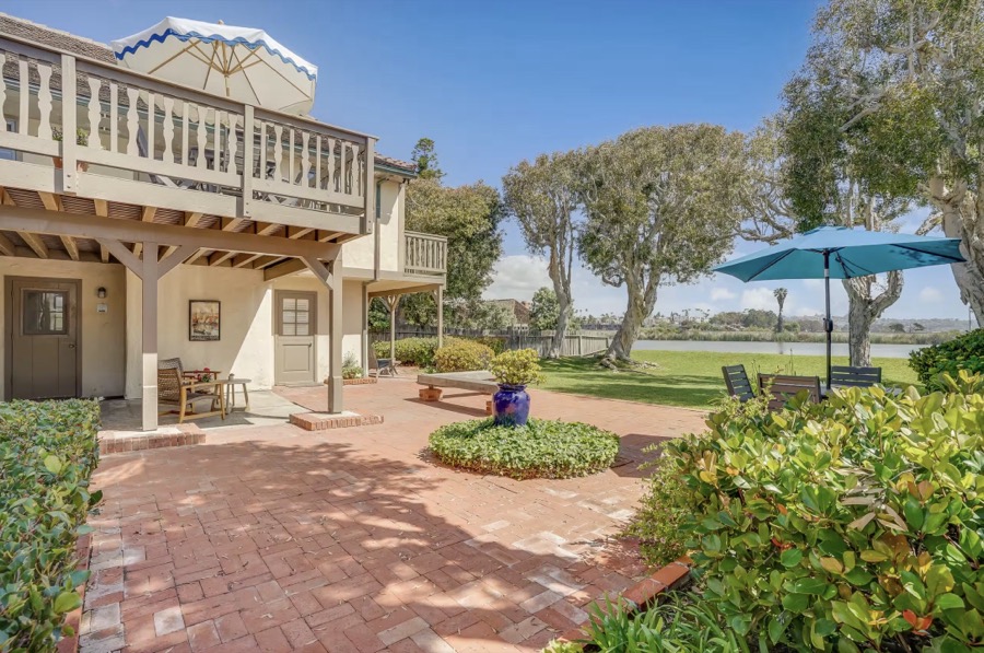 The back of the house above the lawn, umbrellas open toward the lagoon