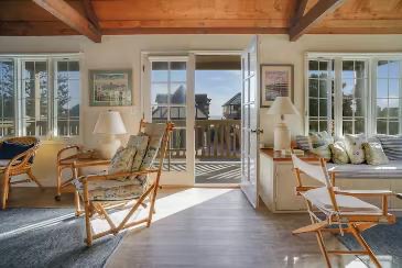 The sunroom with wicker chairs, window seat, and French doors to the balcony