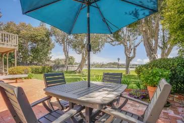 Outdoor dining table under a teal umbrella overlooking the lagoon