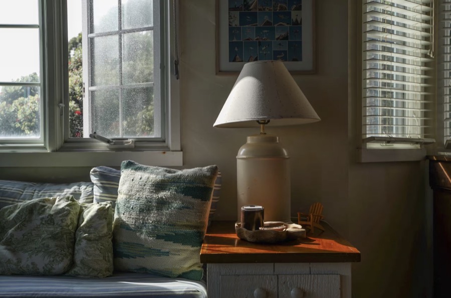 A cushioned window seat with a lamp and the garden beyond
